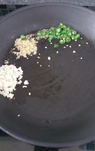 Green chili, chopped garlic and grated ginger in the pan on gas stove.