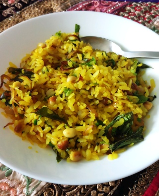 A plate of freshly prepared Kanda Poha topped with cilantro and peanuts.