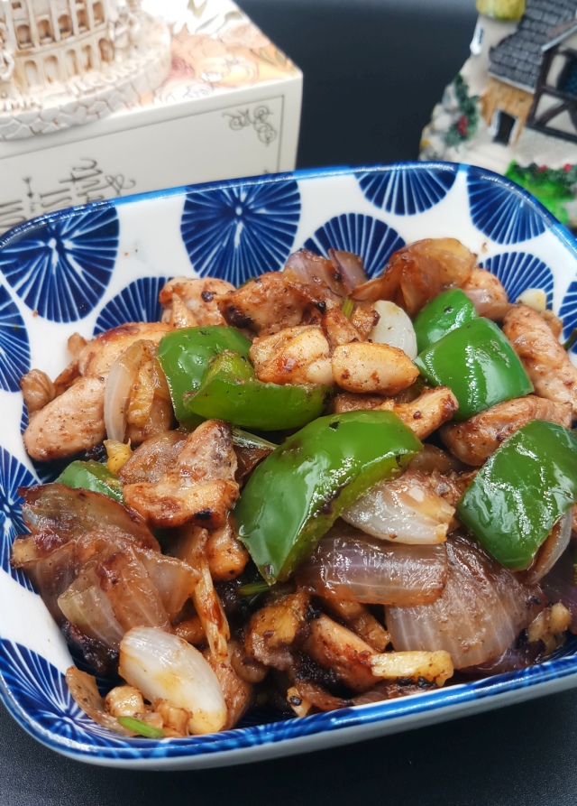 Chicken Stir-Fry is in blue floral bowl on black table.