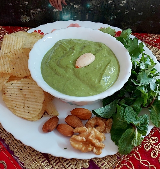 A bowl filled with vibrant green makhmali chutney garnished with soaked almond.