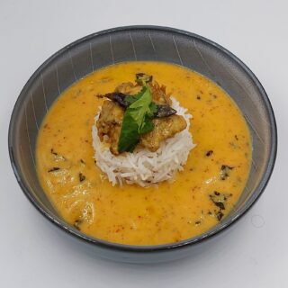 A bowl of Punjabi kadhi served with white rice, garnished with fresh coriander leaves.