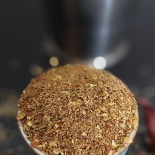 A bowl of dry spice powder mix for Arbi Masala with cumin, coriander, turmeric, and red chili powder.