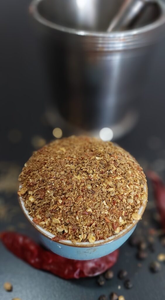 A bowl of dry spice powder mix for Arbi Masala with cumin, coriander, turmeric, and red chili powder.