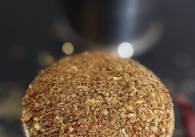 A bowl of dry spice powder mix for Arbi Masala with cumin, coriander, turmeric, and red chili powder.