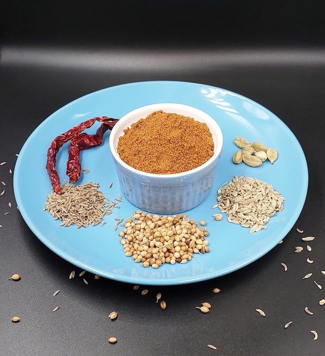 A small bowl of Bengali Bhaja Masala, a traditional spice blend featuring roasted and ground spices, ideal for enhancing the flavors of various Bengali dishes.